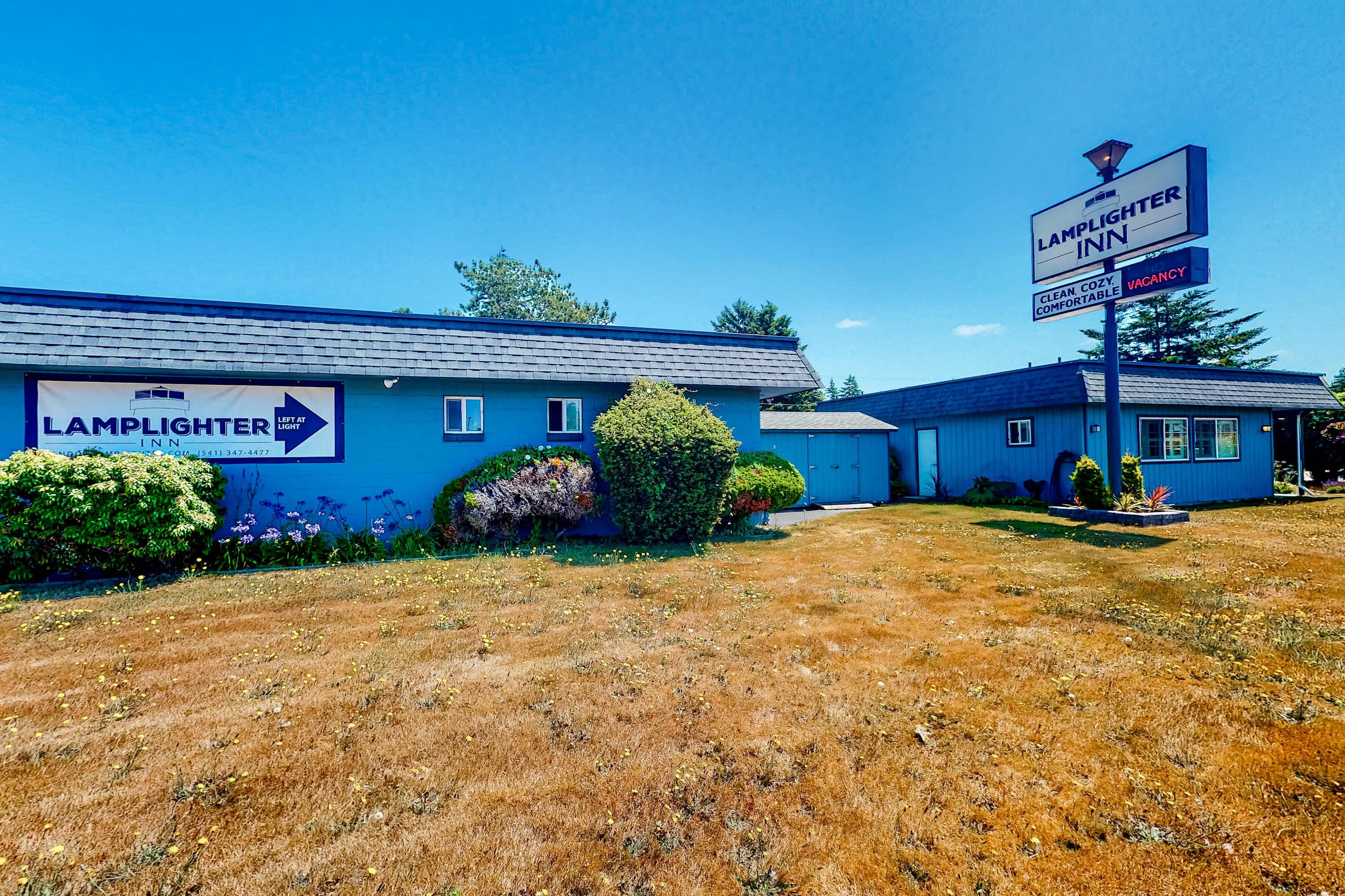 A blue building with a sign for Lamplighter Inn, a vacant sign, and a clear sky.