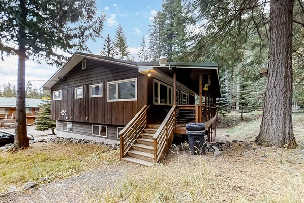 A wooden cabin with a staircase, surrounded by trees.