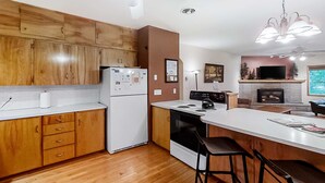 A kitchen with wooden cabinets, a white refrigerator, a stove, and a large island with bar stools. - Large Dog-Friendly Duplex with Lovely Interior + Free WiFi, Private Washer/Dryer (Joseph)