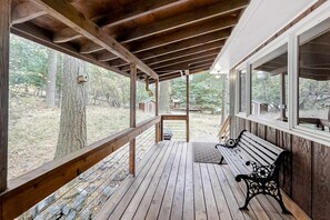 A wooden deck with a bench and a birdhouse.