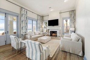 A living room with a fireplace, a television, and a view of the ocean. - Seagrove "Belle Plage" 517 Eastern Lake Rd (Santa Rosa Beach)