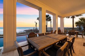 A covered outdoor dining area with a view of the ocean and palm trees. - Seagrove "Belle Plage" 517 Eastern Lake Rd (Santa Rosa Beach)