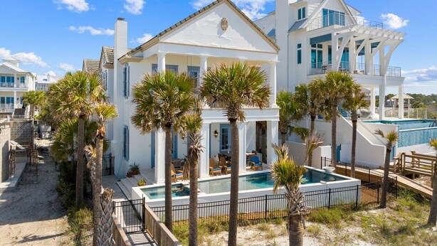 Un'ampia casa bianca con piscina, circondata da palme.