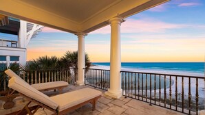 Un balcone coperto con due poltrone, vista sulla spiaggia e una palma.