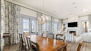 Un'ampia sala da pranzo con un grande tavolo in legno e sedie, un lampadario e un camino.