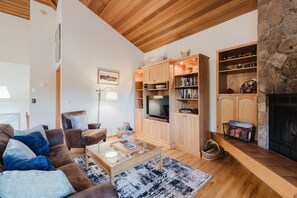 Una sala de estar acogedora con chimenea, estanterías de madera, un televisor y un espacio de descanso confortable.