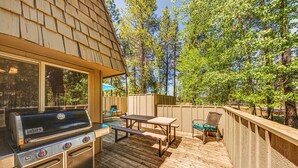 Eine Holzterrasse mit einem Weber-Grill, einem Picknicktisch und Stühlen.