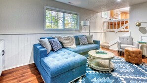 Un salon avec un canapé bleu, une table basse ronde et un tapis à motifs.