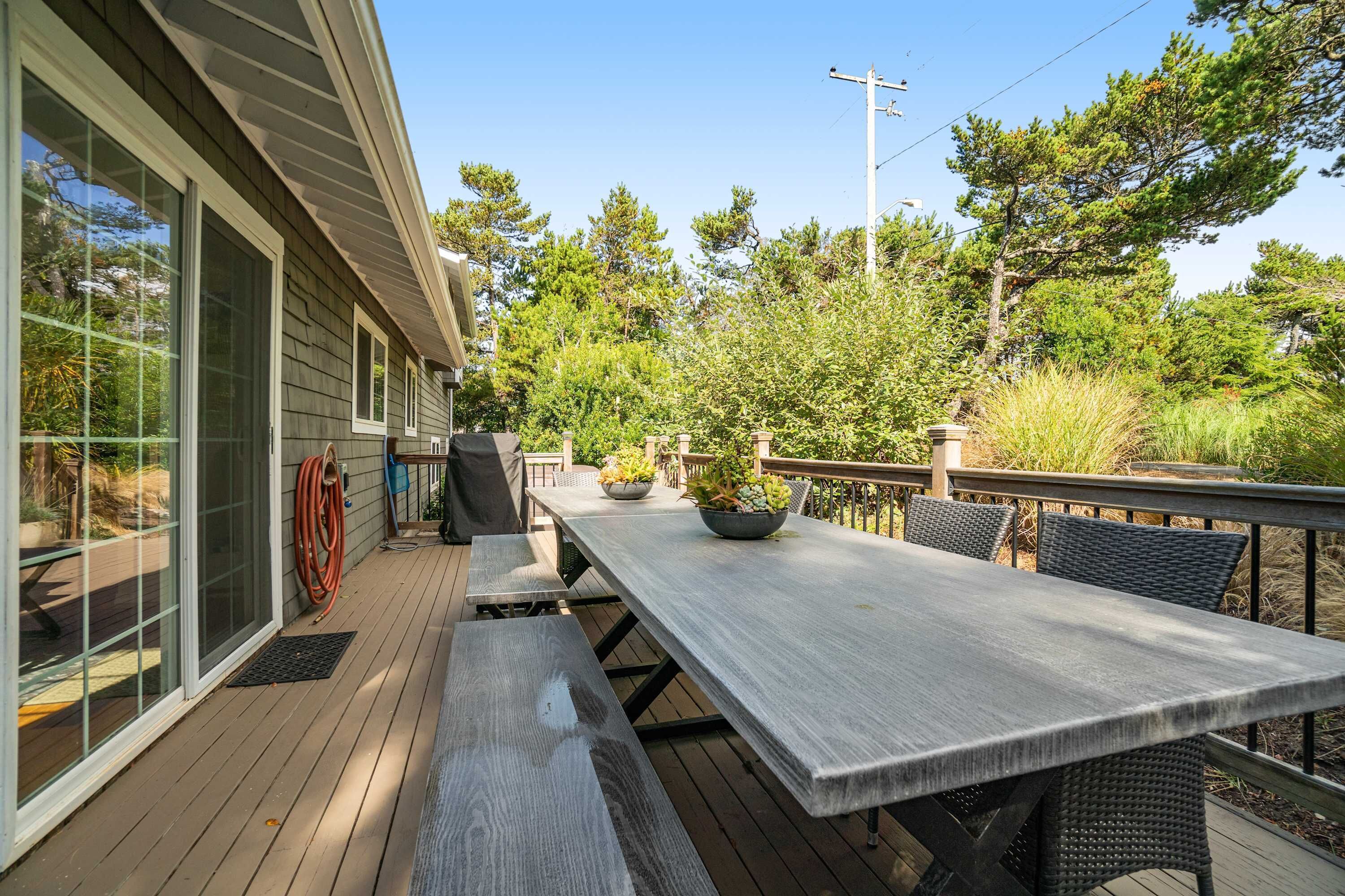 Une terrasse avec une table et des chaises, entourée de verdure.