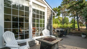 Une terrasse avec des fauteuils Adirondack, un foyer et une table à manger.