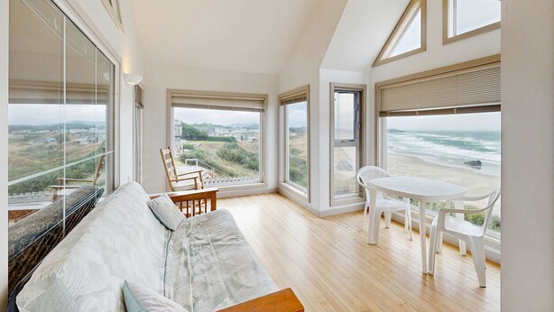 Una habitación con techos altos, ventanas grandes, un sofá, una mesa de comedor y sillas.