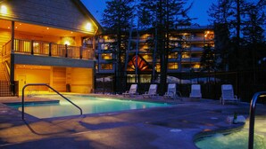 Un hotel con piscina, sdraio e un edificio a più piani con balconi.
