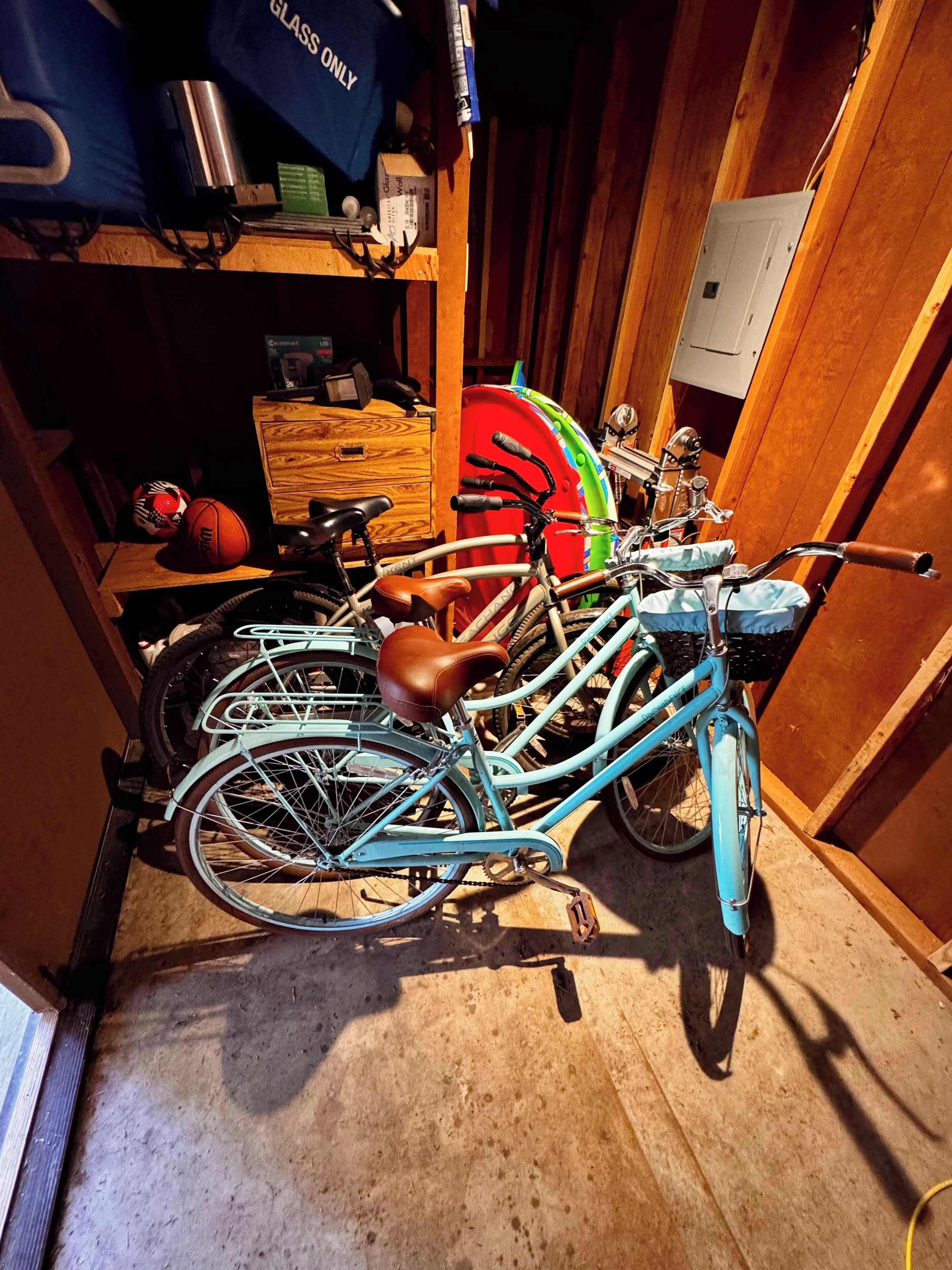A bicycle with a brown seat and a blue frame, leaning against a wooden wall in a room with a concrete floor.