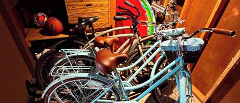 A bicycle with a brown seat and a blue frame, leaning against a wooden wall in a room with a concrete floor.