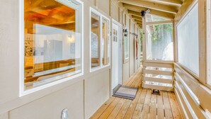 Un pasillo con pisos de madera, paredes blancas y ventanas amplias.