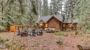 A cabin with a dining area, surrounded by a forest.