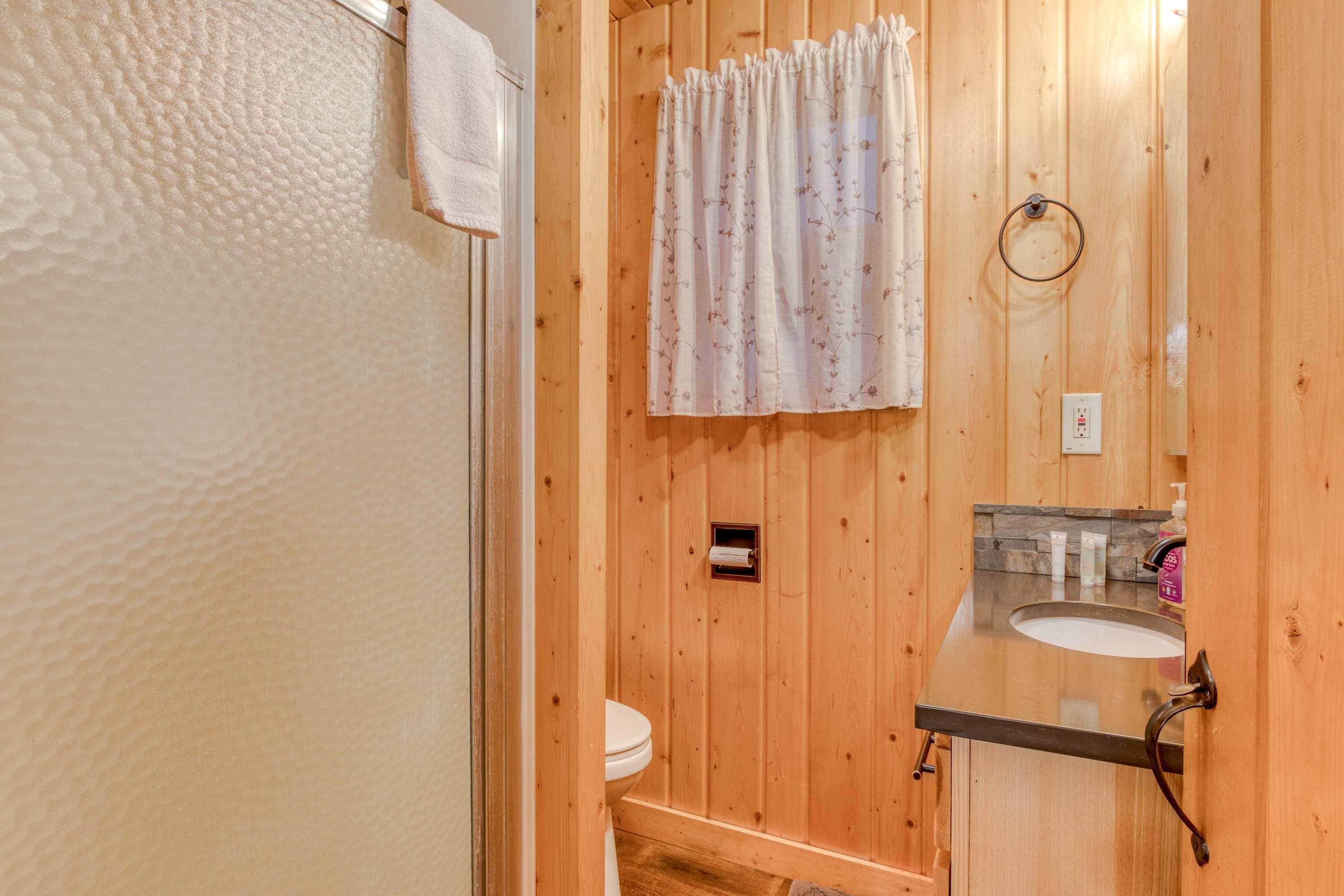 Un baño de madera con inodoro, lavamanos y zona de ducha.