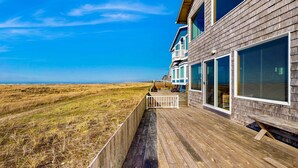 Una terraza de madera con vista a la playa y el océano.