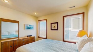 Un dormitorio con cama, cómoda y dos ventanas con persianas.