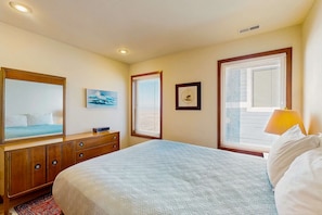 A bedroom with a bed, dresser, and two windows with blinds.