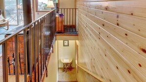 Ein Holzinnenraum mit Treppe, einem kleinen Tisch und Blick durch eine Glastür.