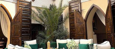 An outdoor patio with a checkered floor, green wicker furniture, and a decorative railing.