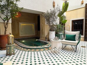 A courtyard with a swimming pool, potted plants, a seating area, and a patterned floor. - Palais Adam (Marrakech)