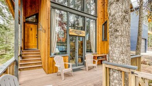 Una baita di legno con un portico, due poltrone Adirondack e un grande tronco d'albero.