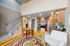 A spacious living area with a staircase, a dining table, a sofa, and a kitchen in the background. - Family- and dog-friendly loft with fast WiFi & full kitchen - walkable location (Joseph)
