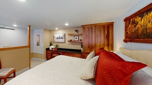 A bedroom with a bed, a desk, a chair, and a painting on the wall.