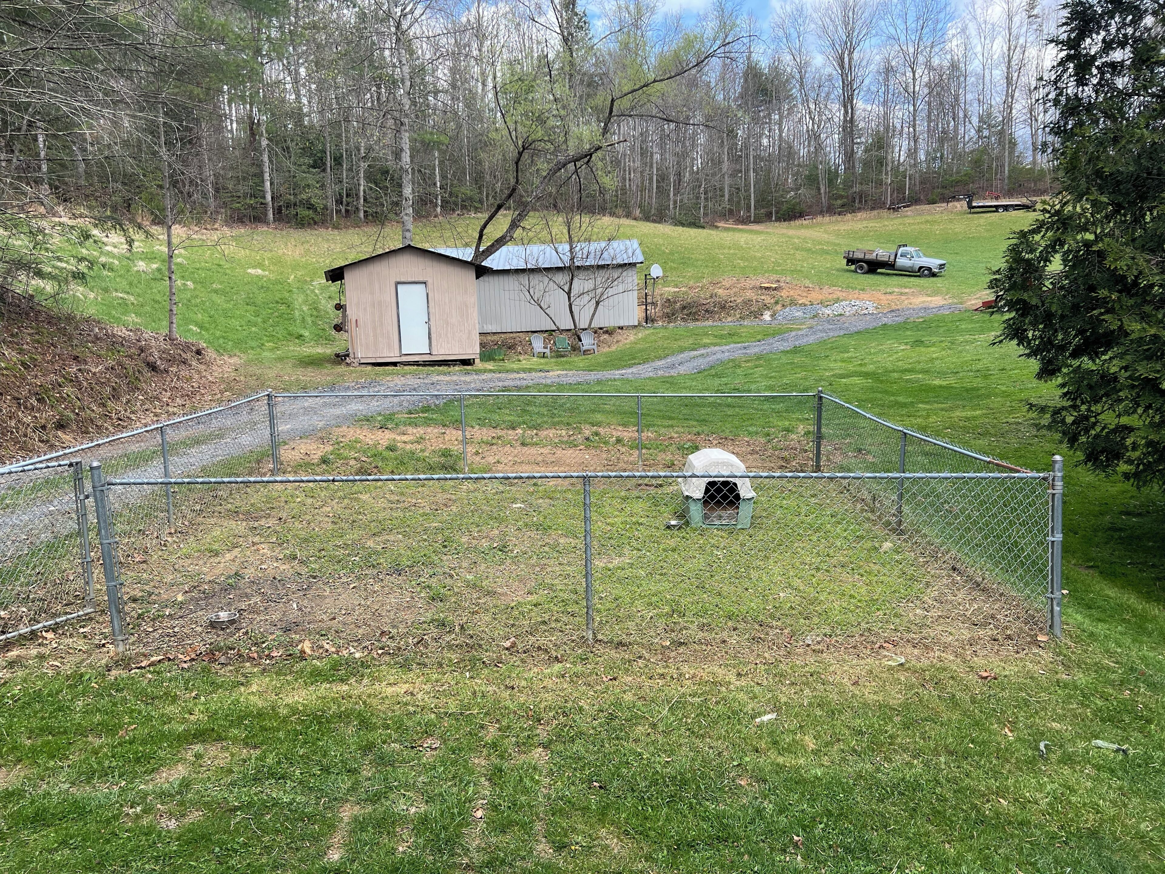 A fenced yard with a small shed, a dog house, and a truck.