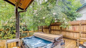 A hot tub on a wooden deck surrounded by a wooden fence and lush greenery.