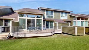 A modern residential building with a covered patio, large windows, and a well-maintained lawn. - Spacious townhouse with fireplace, fast WiFi & resort pools-hot tub-golf (Eagle Crest)
