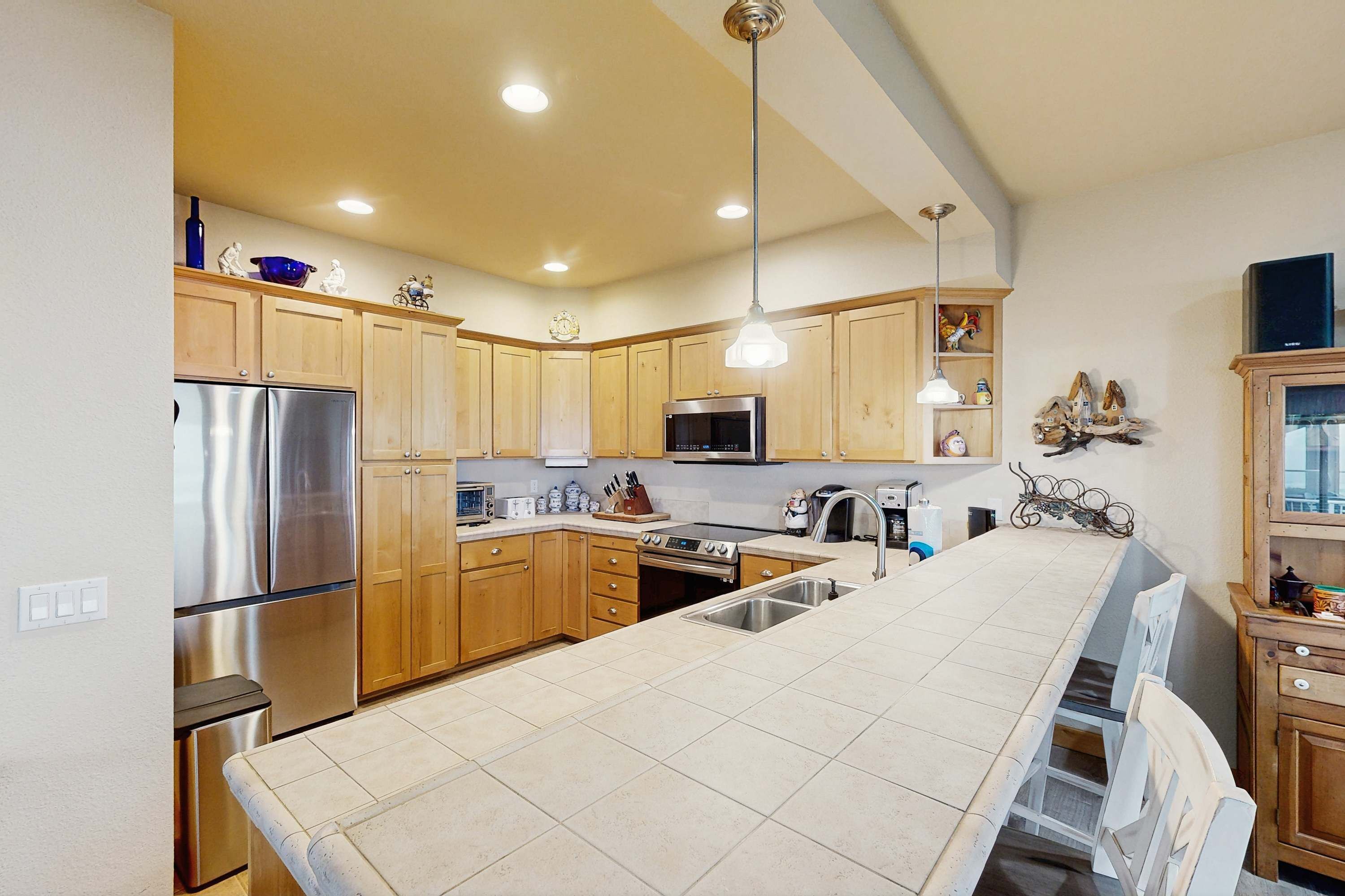 Una cocina con armarios de madera, electrodomésticos de acero inoxidable, una isla grande e iluminación colgante.