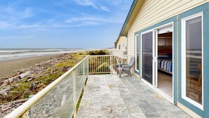 Ein Ferienhaus direkt am Strand mit Balkon, einer Schiebetür zum Schlafzimmer und Blick auf den Strand.