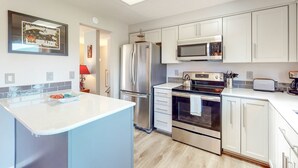 Una cocina moderna con armarios blancos, electrodomésticos de acero inoxidable y una isla central.