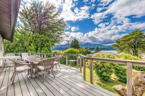 A wooden deck with wicker furniture, a view of mountains, and a clear sky.