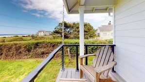 Eine Holzterrasse mit einer Bank, einem Geländer und Blick auf das Meer und Häuser.