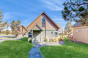 A residential house with a prominent gable roof, a front porch, and a well-maintained lawn. - Beautifully updated, golf-course-front chalet with deck, pools, hot tubs & gyms (Eagle Crest)