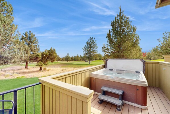 A hot tub on a wooden deck with a view of a golf course. - Beautifully updated, golf-course-front chalet with deck, pools, hot tubs & gyms (Eagle Crest)