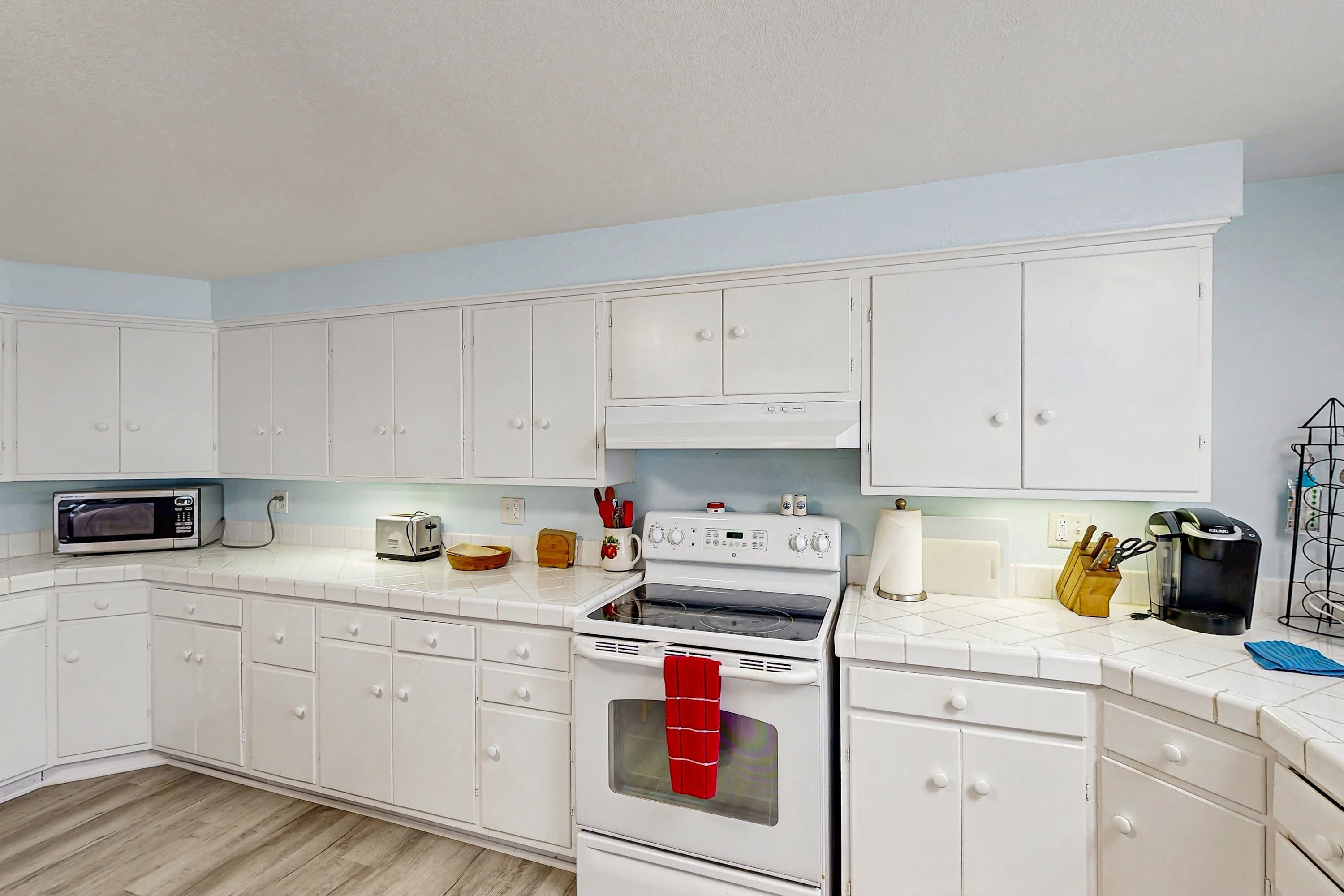A kitchen with white cabinets, a microwave, a toaster, and a stove.