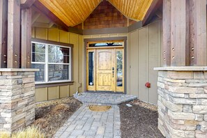 A wooden door with a small porch and stone pillars. - Large comfortable home withfireplaces, deck, & short walk to pool & hot tub (Eagle Crest)
