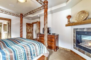 A bedroom with a four-poster bed, a fireplace, a dresser, and a mirror. - Large comfortable home withfireplaces, deck, & short walk to pool & hot tub (Eagle Crest)