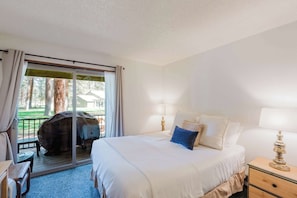 Habitación de hotel con cama, lámparas de noche, escritorio y vistas al exterior.