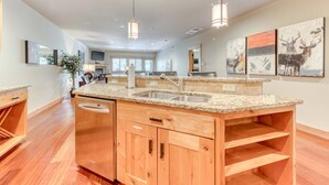 Una cocina amplia con encimeras de granito, armarios de madera e iluminación colgante.