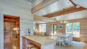 Una cocina amplia con una isla de madera, taburetes de bar y un comedor con sillas blancas.