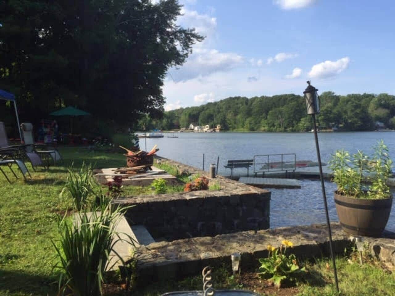 Eine Uferterrasse mit einer Steinsitzbank, einem Blumentopf und einem Laternenpfosten.