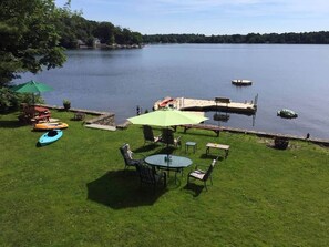Eine Uferterrasse mit Tisch und Stühlen, einem Kanu und einem grünen Sonnenschirm.