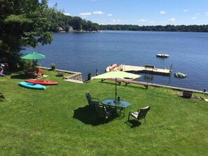 Un patio junto al lago con mesa y sillas, kayaks y un muelle.
