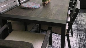 Een eethoek met een houten tafel, bankjes en een klein plantje als decoratie.